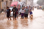 People walk through flooded streets in Valencia, Spain, Wednesday, Oct. 30, 2024. (AP Photo/Alberto Saiz)